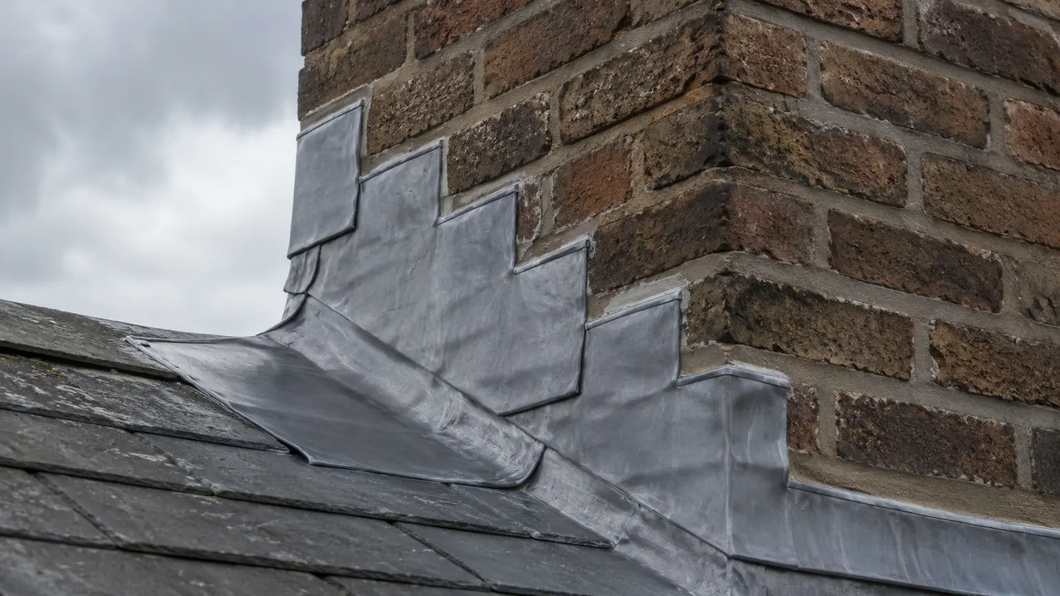 Lead chimney flashing dressed into the brickwork and roof tiles
