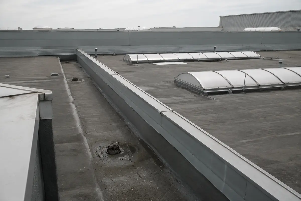 Aerial view of a large commercial flat roof with box gutters and rooflights