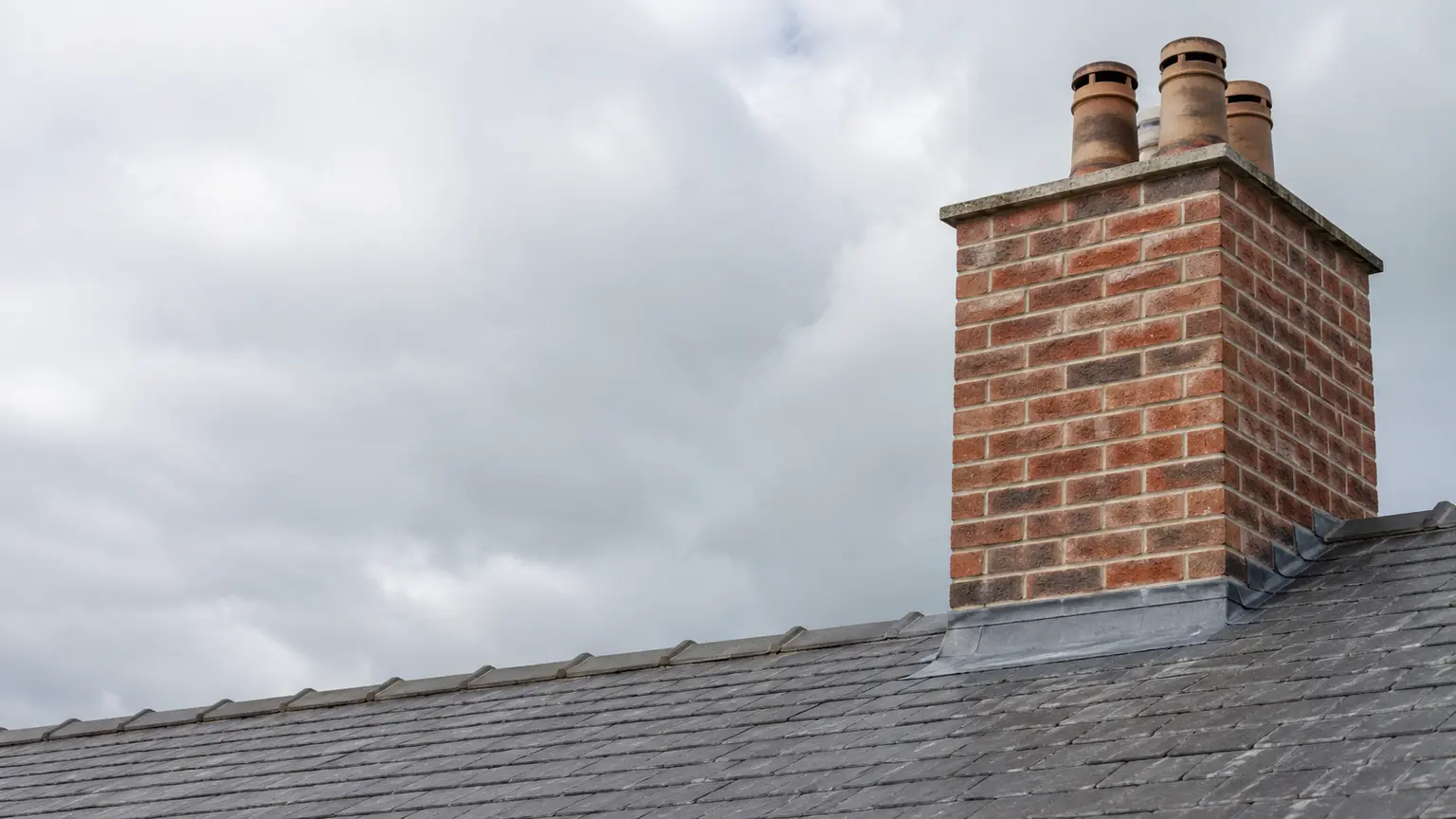 Roofer repointing a chimney and fitting new lead flashing